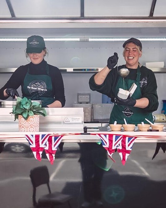 The two sisters behind The Roast Wrap Co. working together at their catering trailer