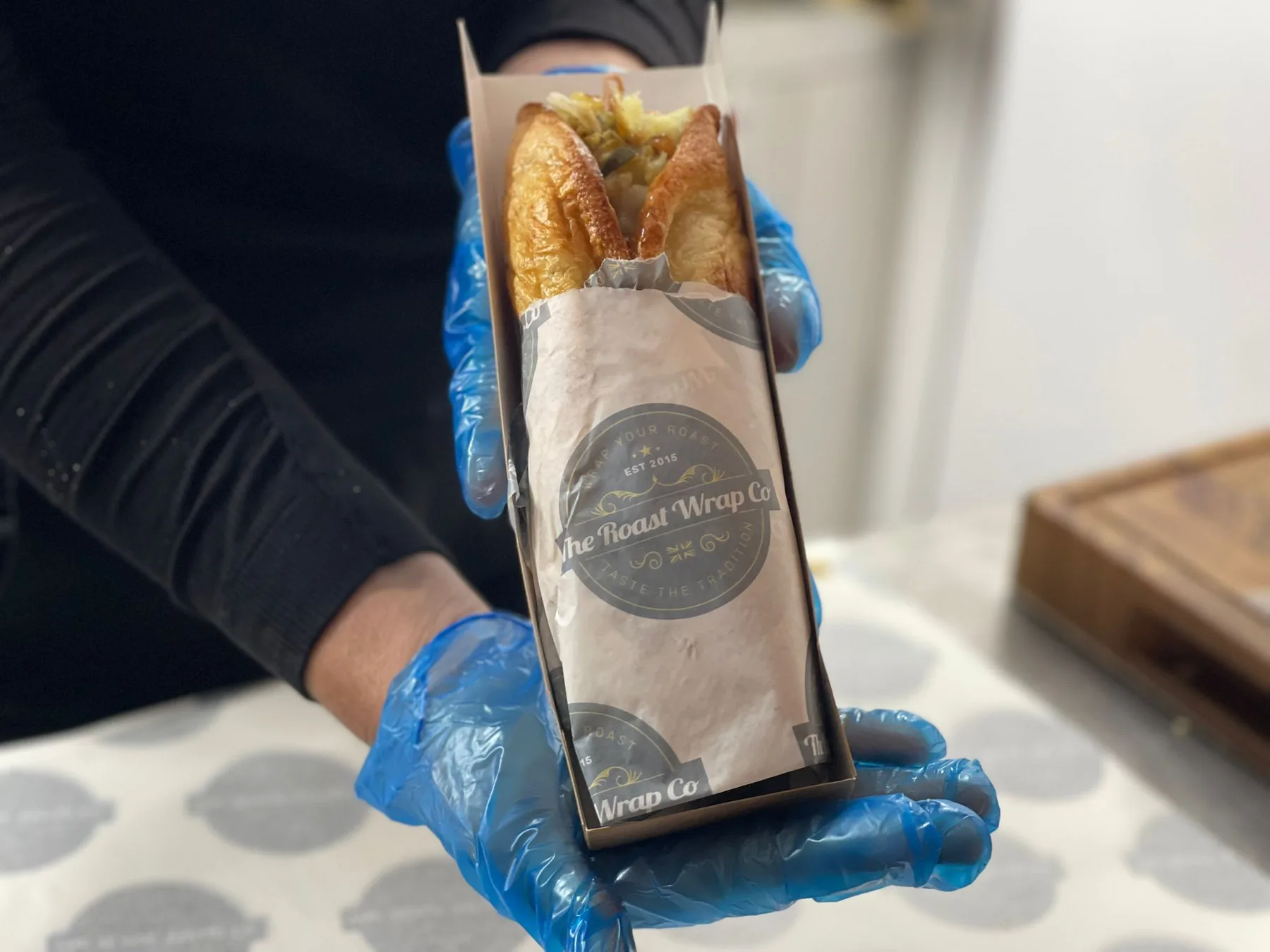 A freshly prepared Roast Wrap held in branded packaging